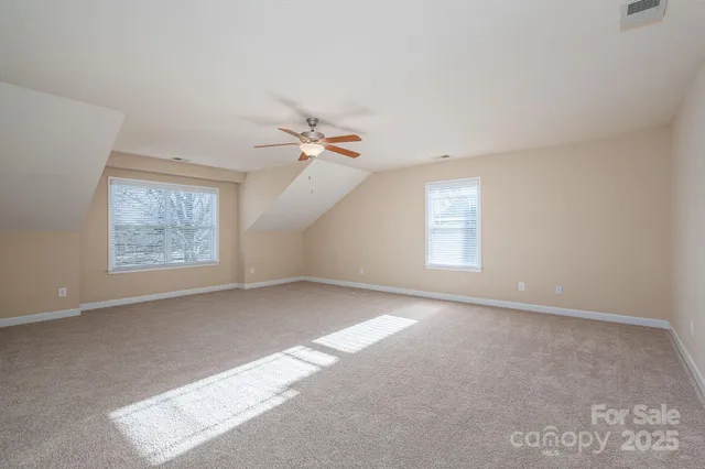 an empty room with windows and chandelier fan