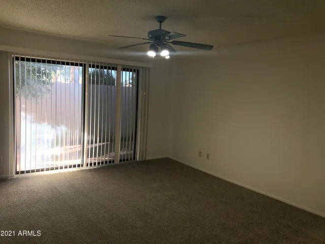 an empty room with a ceiling fan and window