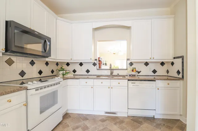 a kitchen with granite countertop white cabinets and white appliances