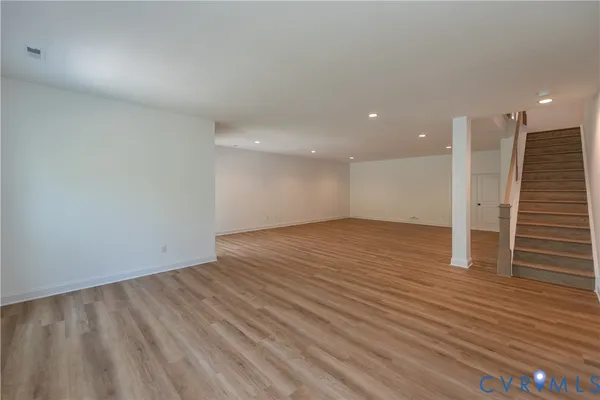 an empty room with wooden floor and entrance to other room