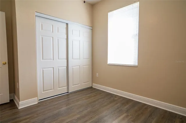 a view of an empty room with wooden floor and closet
