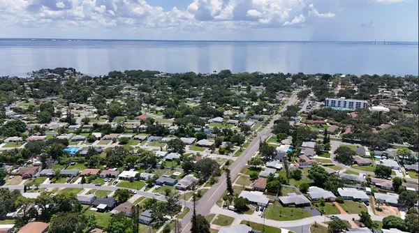 an aerial view of a house with a yard and lake in back