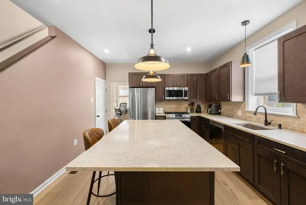 a kitchen with stainless steel appliances a table chairs wooden floors and white cabinets