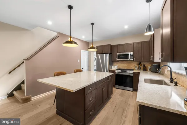 a kitchen with stainless steel appliances granite countertop a sink a stove and a wooden floor