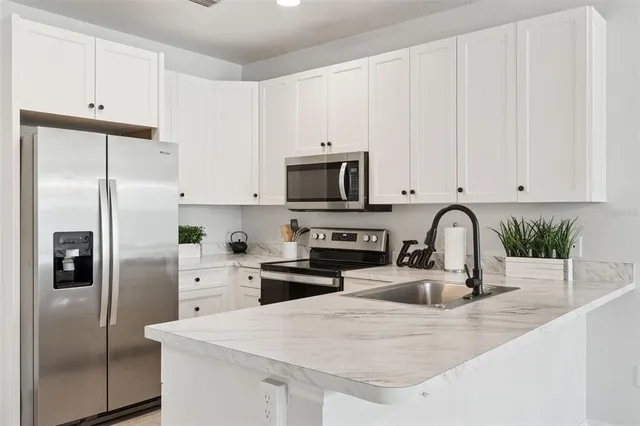 a kitchen with stainless steel appliances granite countertop a refrigerator sink and white cabinets