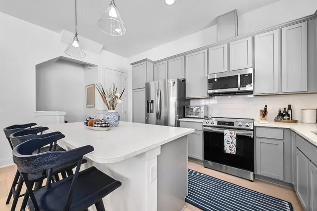 a kitchen with stainless steel appliances granite countertop a stove a refrigerator a sink dishwasher a dining table and chairs with wooden floor