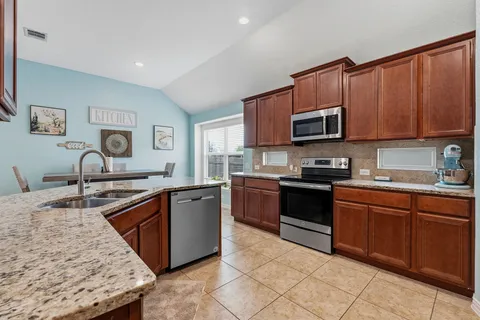 a kitchen with stainless steel appliances granite countertop a stove sink and cabinets