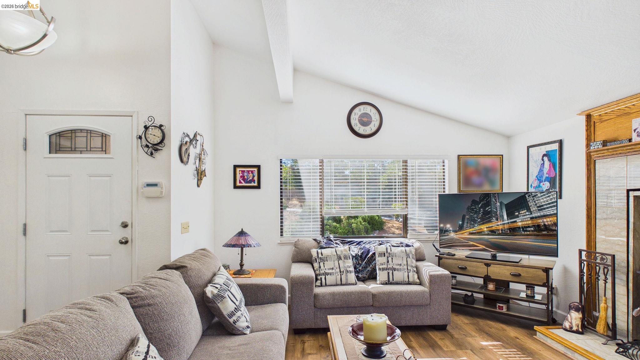 11858 Campo Seco Road Sonora, CA 95370 - Photo 12 of 45 Living area featuring vaulted ceilings with exposed beams, wood-finish flooring, and a white paneled entry door with an arched glass insert