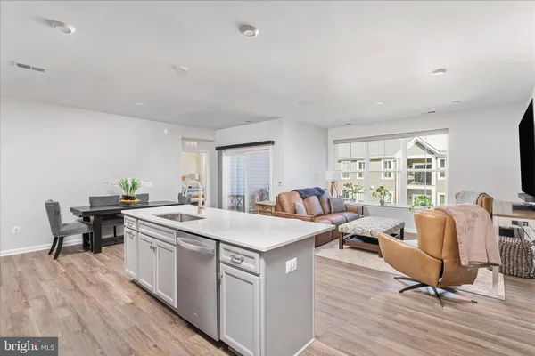 a living room with stainless steel appliances granite countertop furniture and a wooden floor