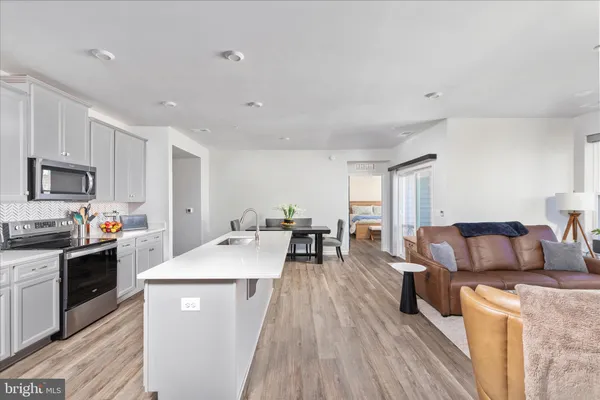 a living room with stainless steel appliances furniture a couch and a kitchen view