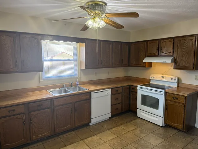 a view of an empty room with chandelier fan and fire place
