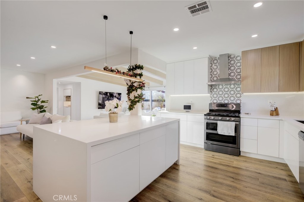 8161 Encino Avenue Northridge, CA 91325 - Photo 36 of 72 a kitchen with stainless steel appliances kitchen island a stove a sink a refrigerator and white cabinets with wooden floor