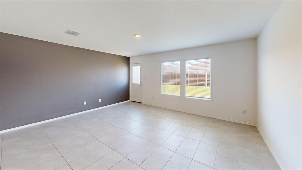 403 Ashbrook Way Princeton, TX 75407 - Photo 8 of 23 Spacious room featuring light-toned tile flooring, a contrasting accent wall, and multiple windows with blinds