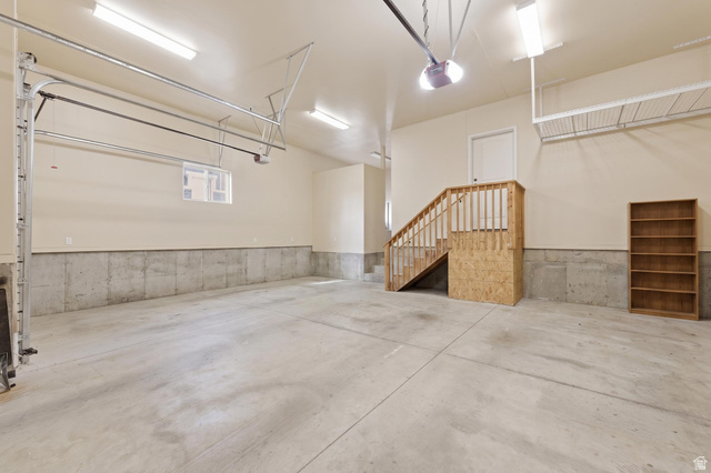 441 South 2080th Street East Springville, UT 84663 - Photo 40 of 64 Spacious garage with concrete flooring, fluorescent overhead lighting, and an internal staircase with wood railings