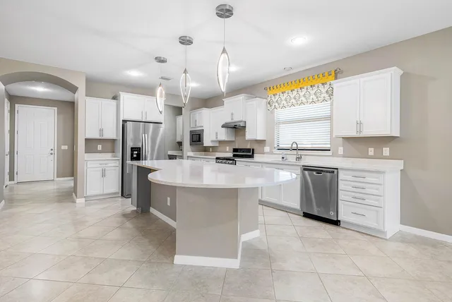 a kitchen with stainless steel appliances granite countertop a sink a stove and a refrigerator