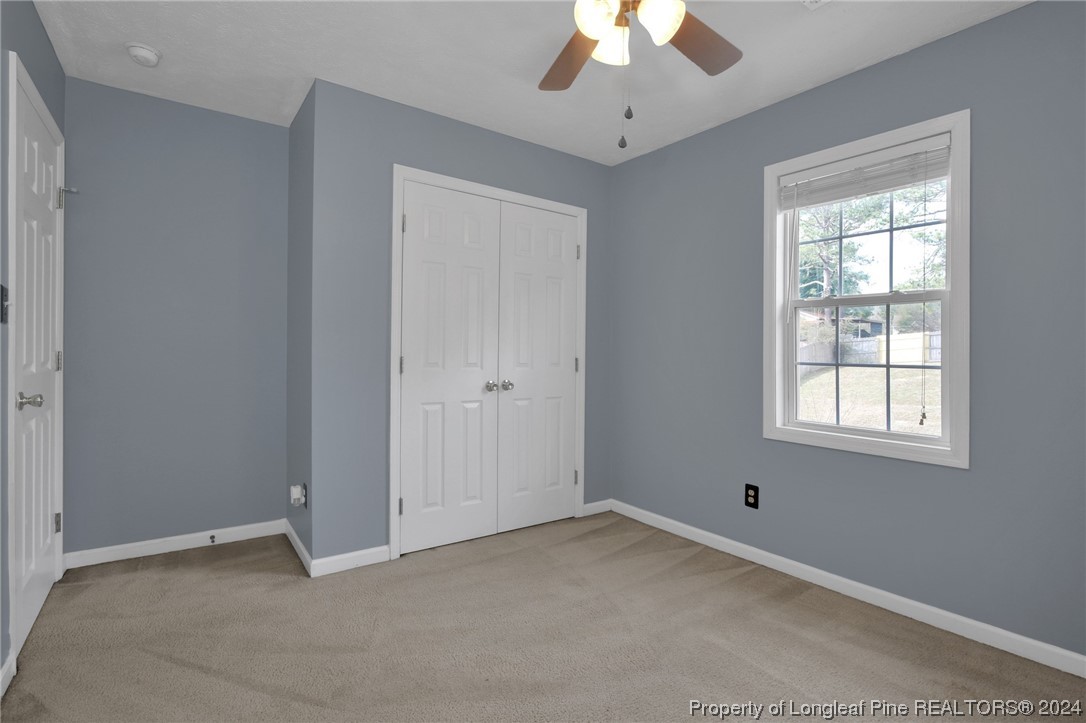 5808 Spreading Branch Road Hope Mills, NC 28348 - Photo 29 of 35 an empty room with a chandelier fan and windows