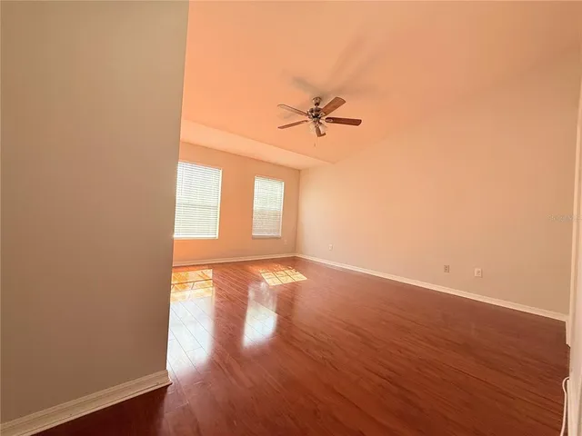 a view of empty room with wooden floor and fan