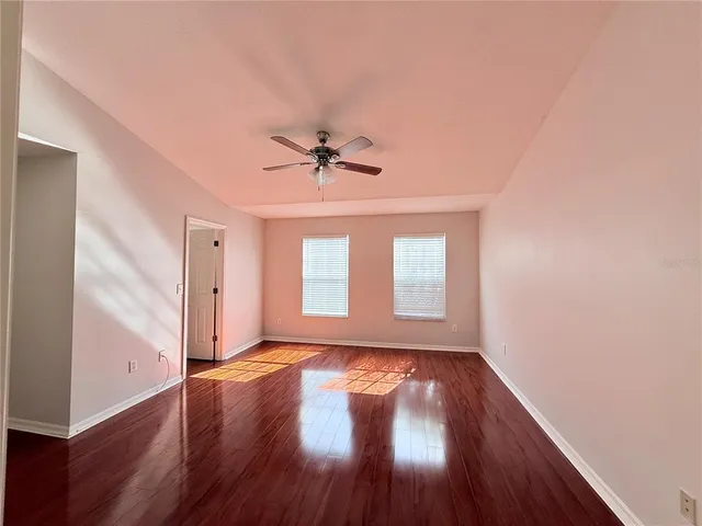 a view of an empty room with a window and wooden floor