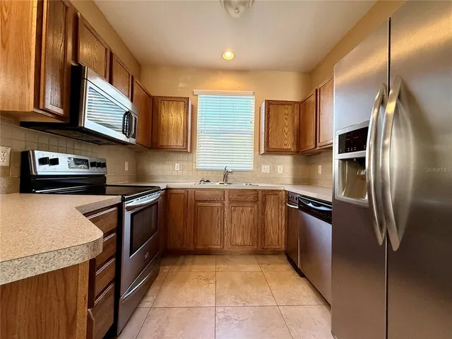 a kitchen with stainless steel appliances granite countertop a stove a sink and a refrigerator