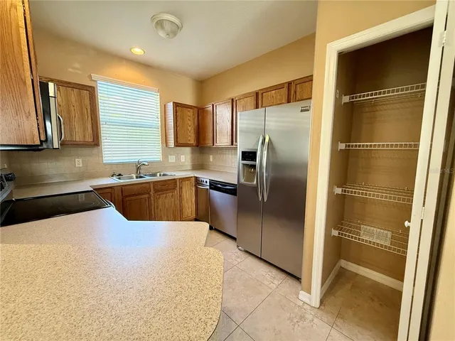 a large kitchen with stainless steel appliances granite countertop a refrigerator and a sink
