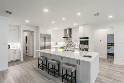 a large kitchen with kitchen island white cabinets and stainless steel appliances