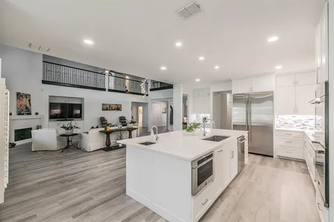 a large white kitchen with a large window and stainless steel appliances