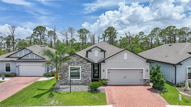 a view of a white house next to a yard with potted plants