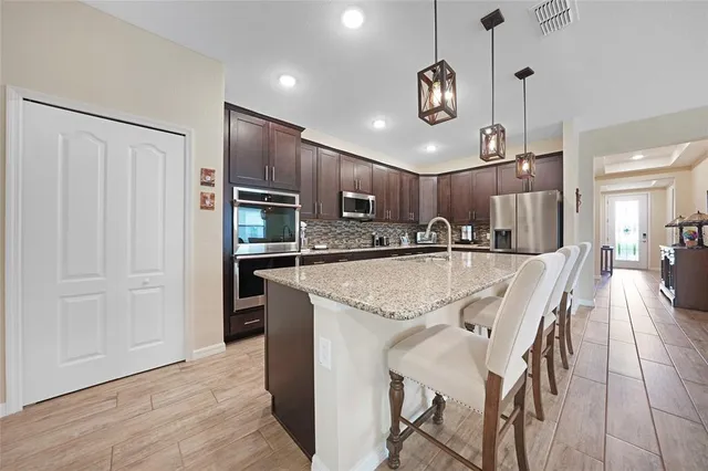a kitchen with stainless steel appliances granite countertop a sink refrigerator and cabinets
