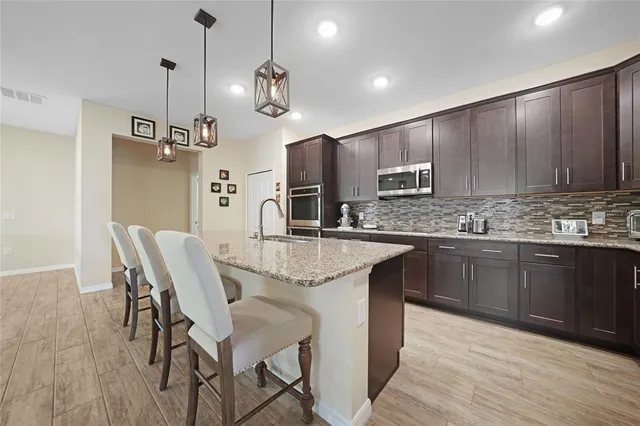 a kitchen with kitchen island granite countertop wooden floors and wooden cabinets