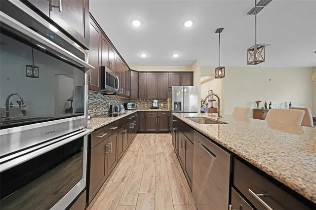 a kitchen with stainless steel appliances granite countertop sink a refrigerator and wooden cabinets