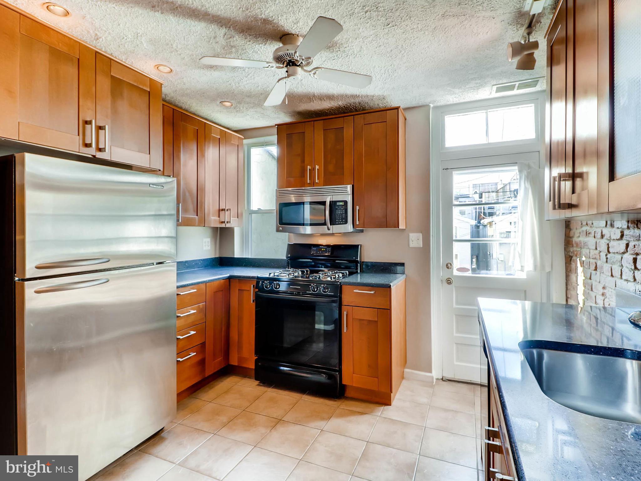1212 Riverside Avenue Baltimore, MD 21230 - Photo 9 of 27 a kitchen with stainless steel appliances granite countertop a refrigerator a stove and a sink with wooden cabinets