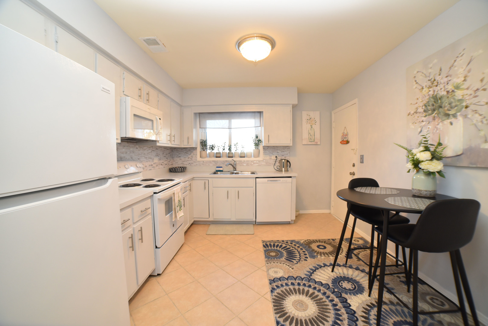 704 Cobblestone Circle, Unit 3E Glenview, IL 60025 - Photo 10 of 21 a kitchen with stainless steel appliances a white stove top oven a sink a dining table and chairs with wooden floor