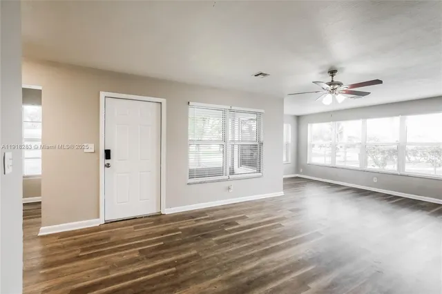 a view of an empty room with a window and wooden floor