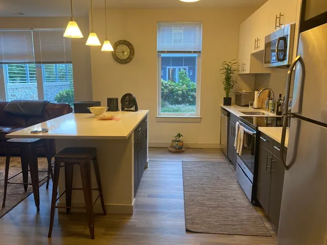 a kitchen with stainless steel appliances granite countertop a stove a sink dishwasher and a refrigerator with wooden floor