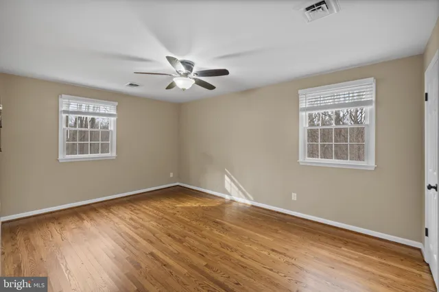 a view of empty room with wooden floor and fan