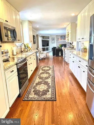 a large kitchen with stainless steel appliances wooden floor a stove and a refrigerator