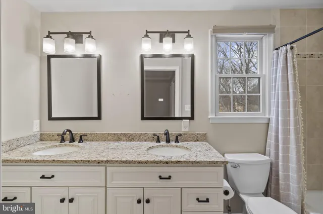 a bathroom with a granite countertop toilet sink and mirror
