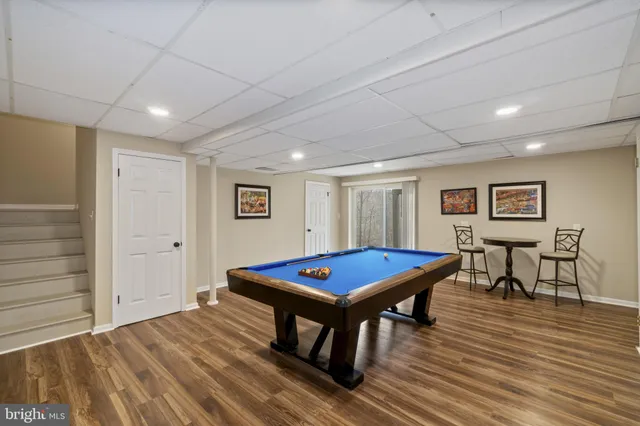 a living room with pool table and a wooden floor