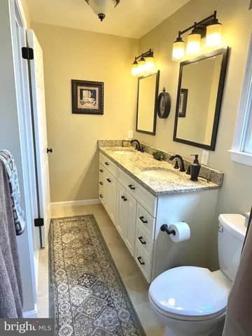 a bathroom with a granite countertop toilet sink and mirror