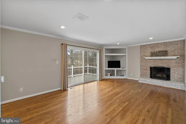 a view of an empty room with wooden floor and a fireplace