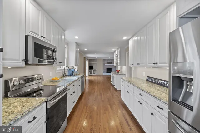 a large kitchen with stainless steel appliances granite countertop a lot of counter space and wooden floors