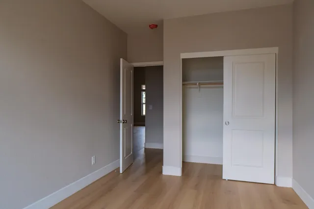 a view of an empty room with closet and wooden floor