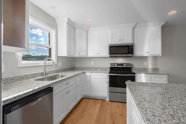 a kitchen with granite countertop a sink a stove and cabinets