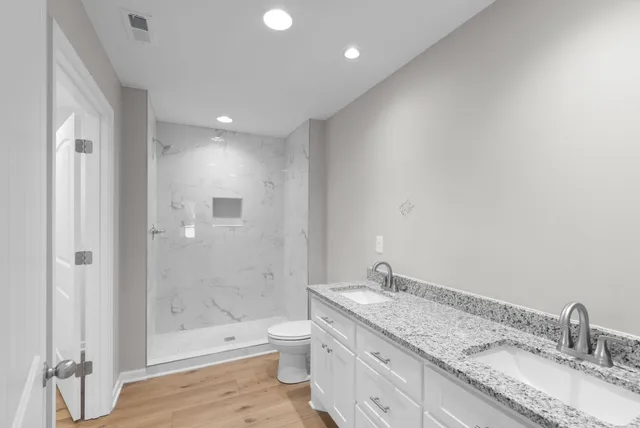 a bathroom with a granite countertop sink a toilet and shower
