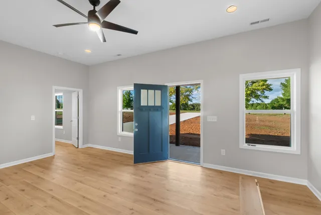 a view of an empty room with a window and wooden floor