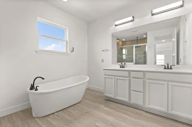 a bathroom with a white tub a sink and mirror