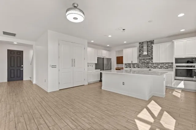 a large white kitchen with white cabinets and wooden floor