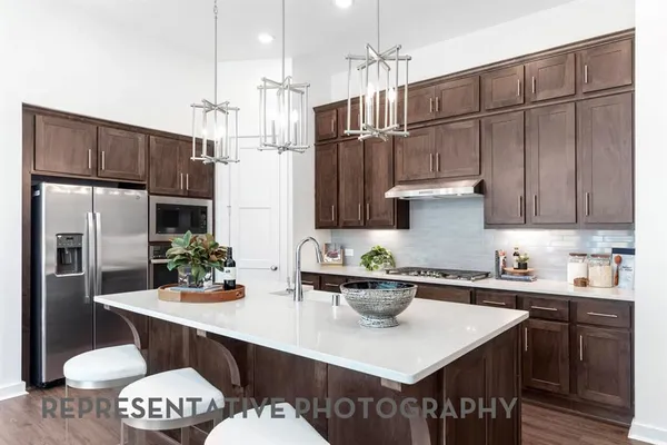 a kitchen with stainless steel appliances a sink dishwasher a refrigerator and a dining table with wooden floor