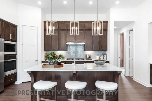 a kitchen with stainless steel appliances granite countertop a kitchen island a stove a table and chairs