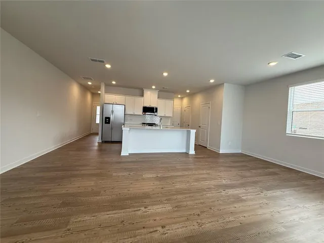 a view of kitchen with kitchen island a sink wooden floor appliances and cabinets